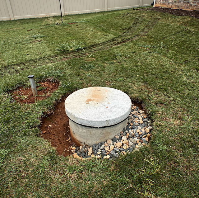 septic tank lid lifted by service technician in backyard